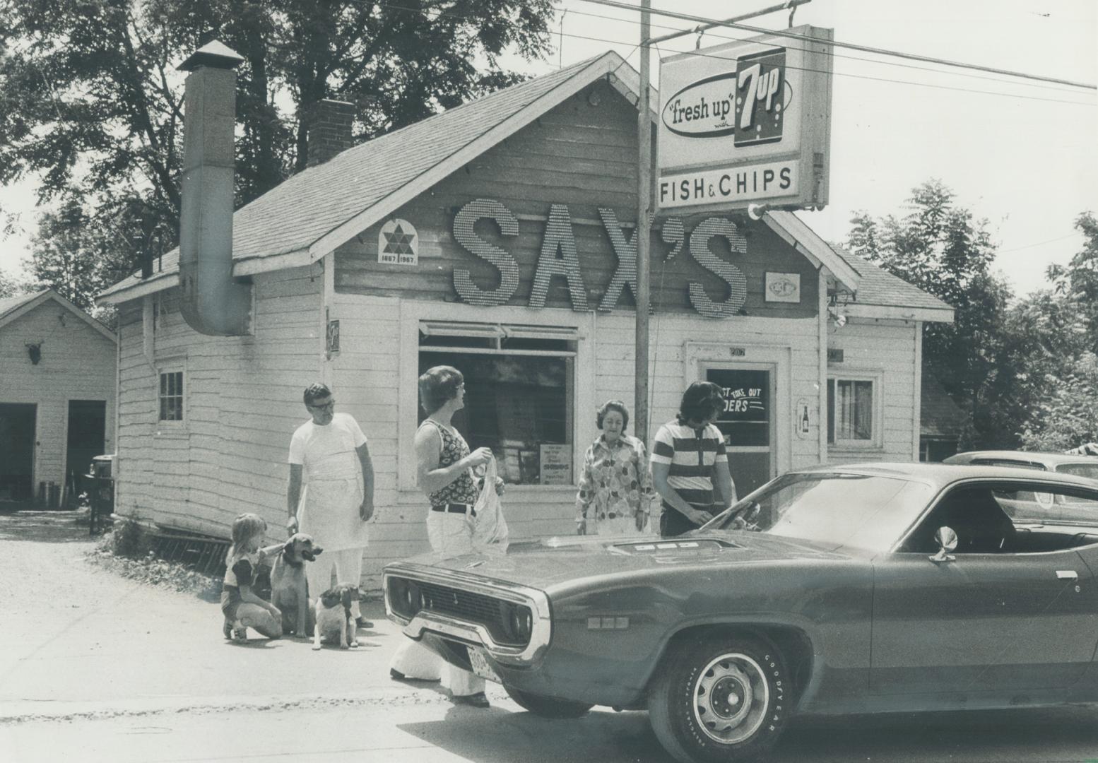 A group of people standing in front of a restaurant</p>
<p>Description automatically generated