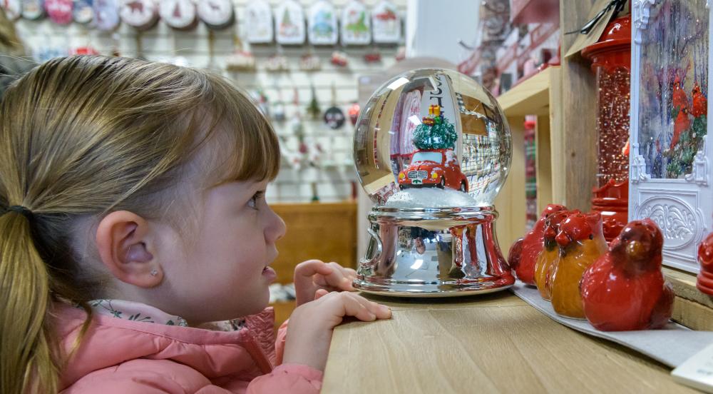 young girl looking at snow globe in shop