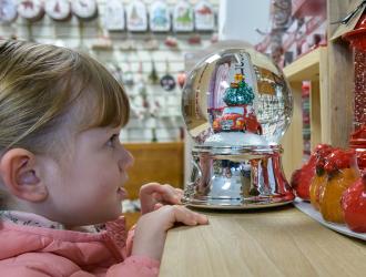 young girl looking at snow globe in shop